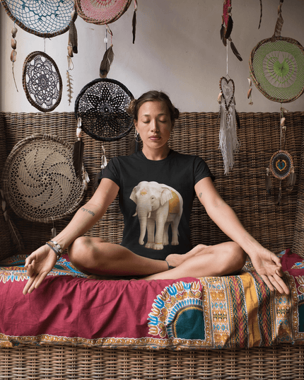 Frau meditiert in elegantem Ambiente, trägt ein Weißer Elefant Damen T-Shirt mit majestätischem Elefantenmotiv.