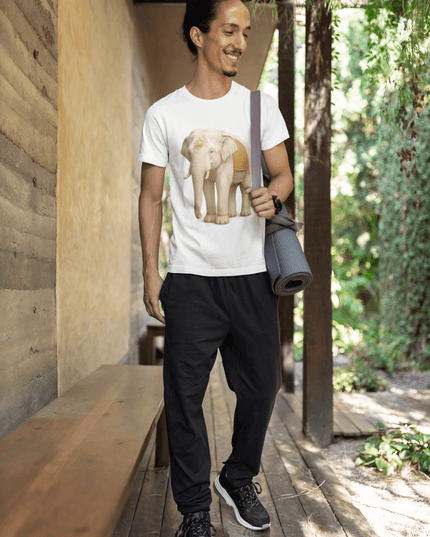 Mann in einem Weißer Elefant Herren T-Shirt mit Yogamatte in der Hand in einer grünen Umgebung.